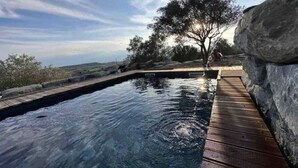 A swimming pool with a wooden deck, surrounded by a stone wall and trees. - Logement Paisible - Mas Sogusthenna (Mons)