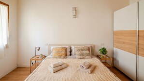 A neatly arranged bedroom with a large bed, two bedside tables, a bedside lamp, and a potted plant. - Ca Mantoet Valdobbiadene - 3Bedroom Loft (Valdobbiadene)
