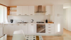 A modern kitchen with white cabinets, stainless steel appliances, and a glass backsplash. - Ca Mantoet Valdobbiadene - 3Bedroom Loft (Valdobbiadene)