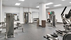 Ett gym med olika typer av träningsutrustning, inklusive styrketräningsmaskiner och konditionsmaskiner.