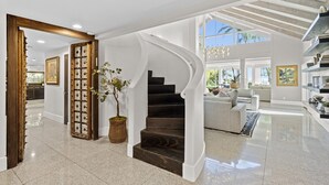 Een ruime woonkamer met een gebogen trap, een groot raam en een modern interieur.