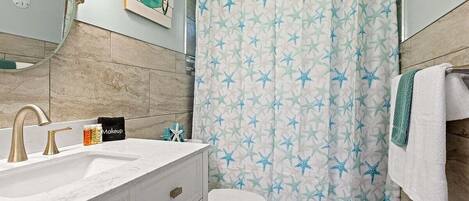 A bathroom with a white sink, gold faucets, a white toilet, and a shower curtain with star patterns.