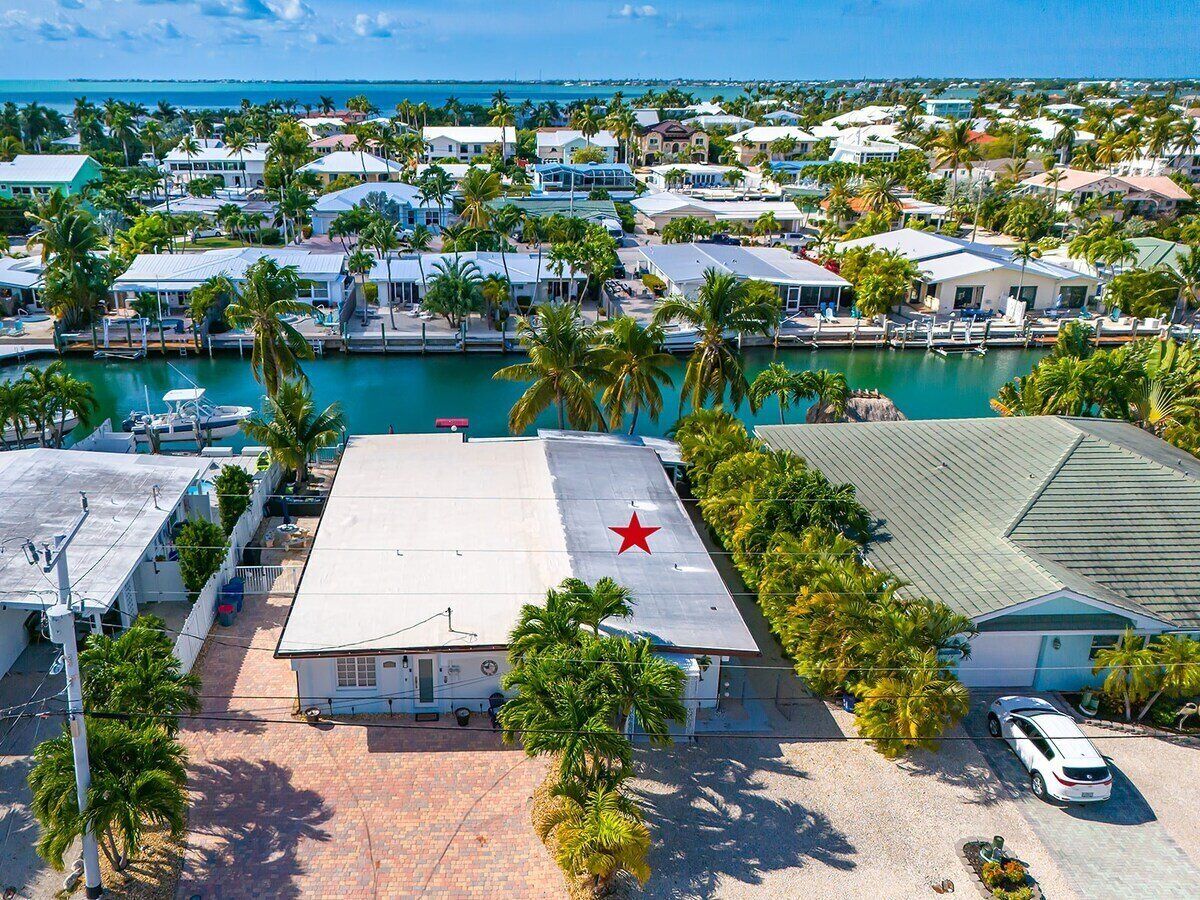 A coastal residential area with houses, a marina, and a prominent red star on a building roof.