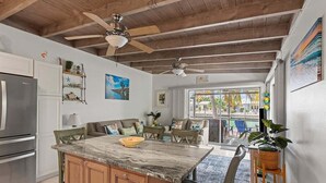 Una cocina con una isla de mármol, armarios de madera y un ventilador de techo.