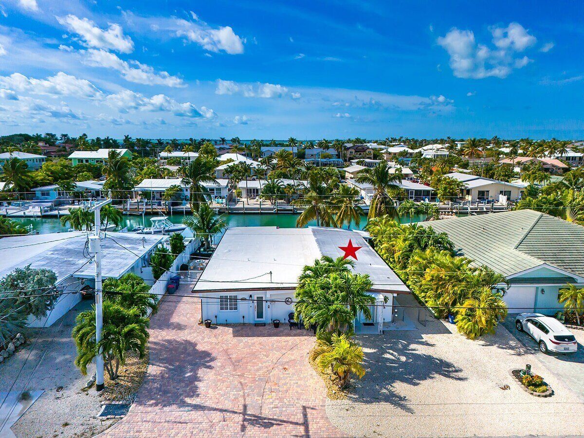 A residential area with houses, a marina, and a building with a red star on the roof.