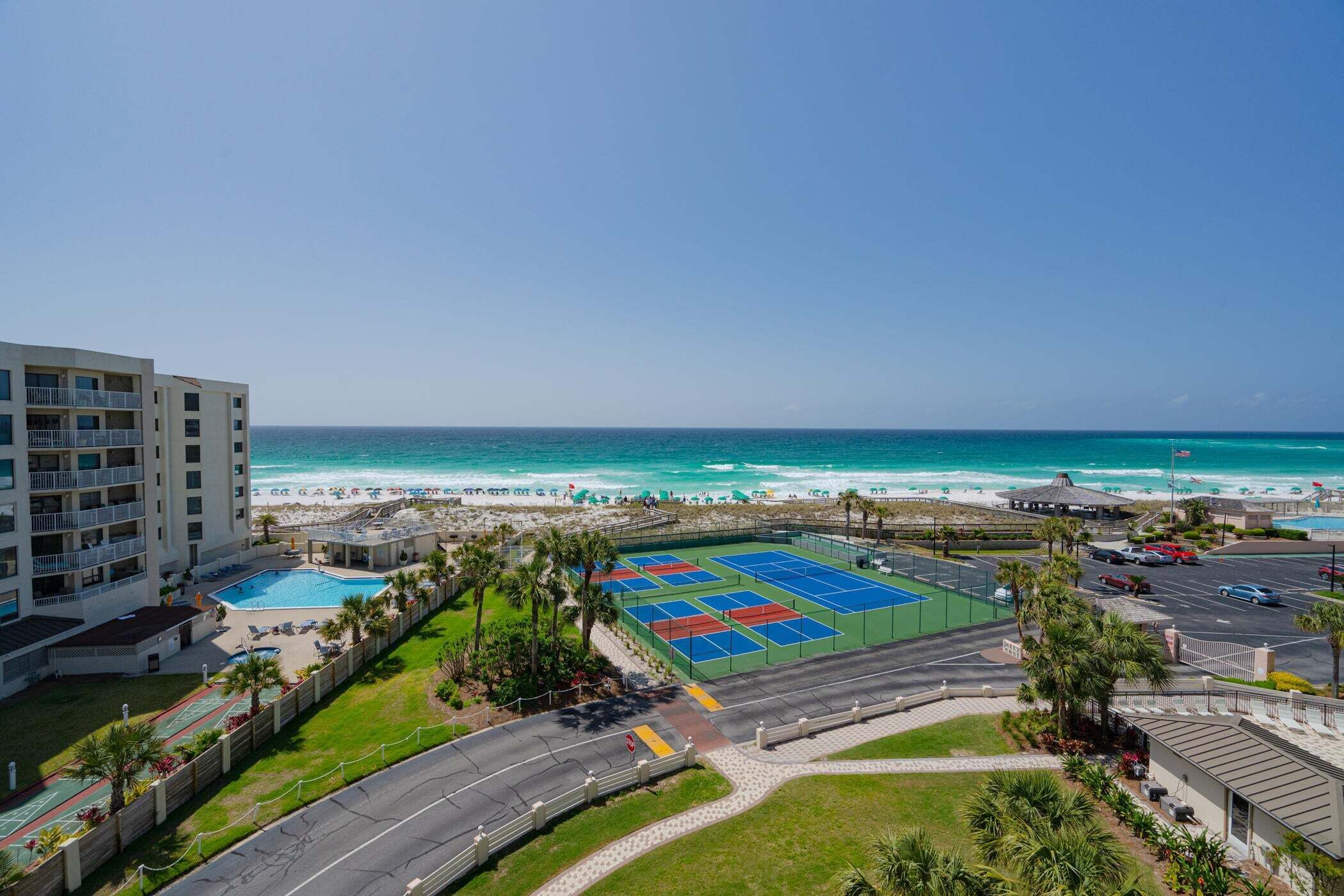 A beachfront property with a tennis court, pool, and ocean view.