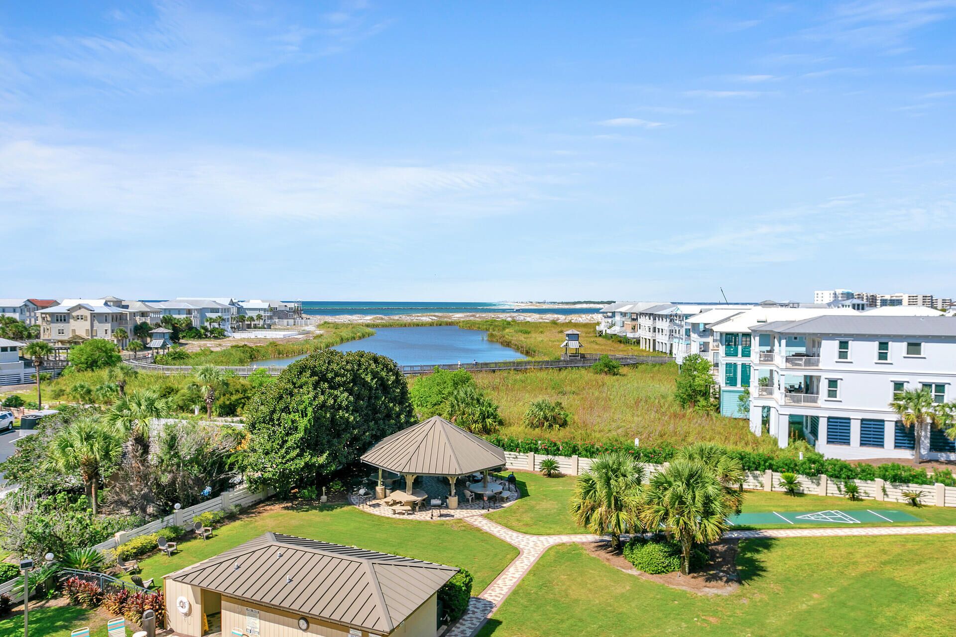 A residential area with a gazebo, a tennis court, and a view of the beach.