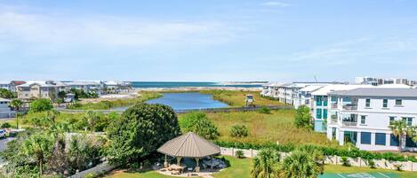 A residential area with a gazebo, a tennis court, and a view of the beach.