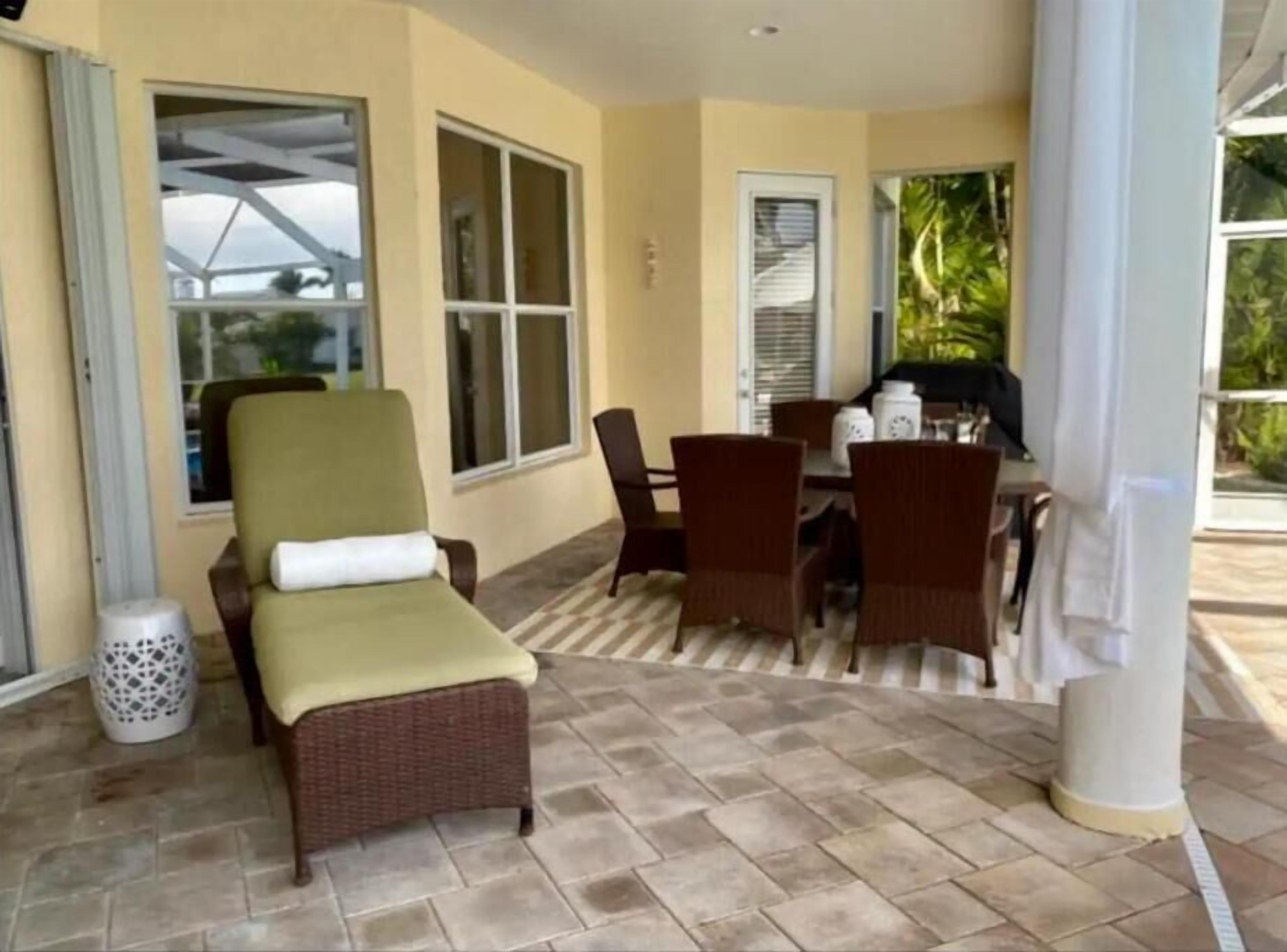 A covered patio area with wicker furniture, a table, and chairs.