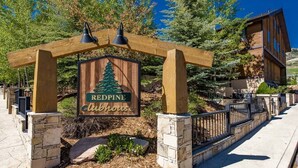 A wooden sign with a pine tree and the words "Redpine Clubhouse" under a wooden pergola.
