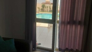 A room with a sliding glass door leading to a pool area. - La bonita compound  (El Gouna)