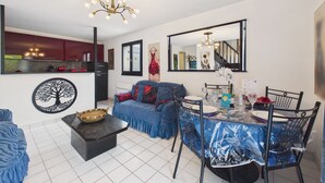 A modern living room with a dining area, a chandelier, a large mirror, and a kitchen visible in the background. - La Tranche-sur-Mer, house for 3 adults / 2 children (La Tranche-sur-Mer)