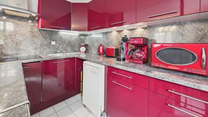 A kitchen with red cabinets, a built-in microwave, a coffee maker, and a dishwasher. - La Tranche-sur-Mer, house for 3 adults / 2 children (La Tranche-sur-Mer)
