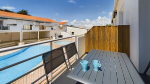 Un balcón con piscina, dos tazas azules y una valla de madera.