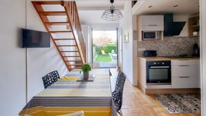 Une cuisine moderne équipée d’un four à micro-ondes et d’un four encastrés, ainsi que d’un escalier en bois menant à un espace extérieur.
