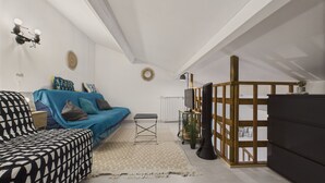 Un salon moderne avec un canapé bleu, un canapé à motifs noirs et blancs, et un meuble TV en bois.