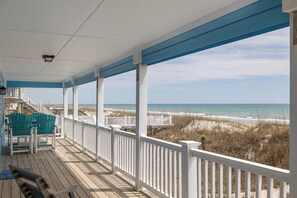 A covered porch with a view of the beach, white railings, and two green Adirondack chairs. - Harbor Lights, Oceanfront House in Emerald Isle, NC! (Emerald Isle)