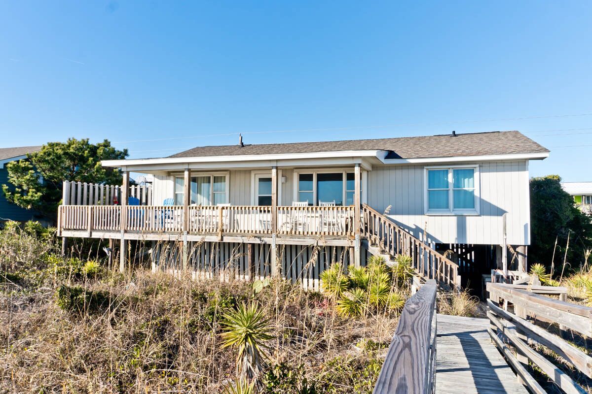 A two-story house with a wooden deck and a small porch.