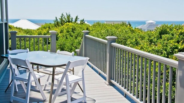 A deck with a table and chairs, overlooking a lush green landscape and the sea. - Hollandaise, Oceanview House in Emerald Isle, NC! (Emerald Isle)