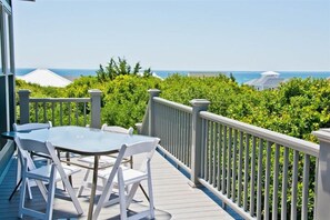 A deck with a table and chairs, overlooking a lush green landscape and the sea. - Hollandaise, Oceanview House in Emerald Isle, NC! (Emerald Isle)