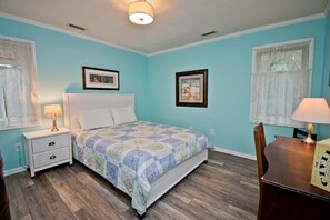 A bedroom with a bed, nightstand, lamp, and a framed picture on the wall. - Hollandaise, Oceanview House in Emerald Isle, NC! (Emerald Isle)