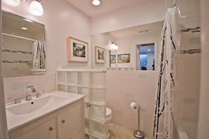 A modern bathroom with a glass shower enclosure, a white sink with a mirror, and a toilet. - Hollandaise, Oceanview House in Emerald Isle, NC! (Emerald Isle)