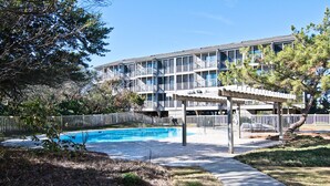 A hotel with a pool, outdoor seating, and a covered patio area. - Island Beach Racquet Club 303A, Oceanfront Condo in Atlantic Beach, NC! (Atlantic Beach)