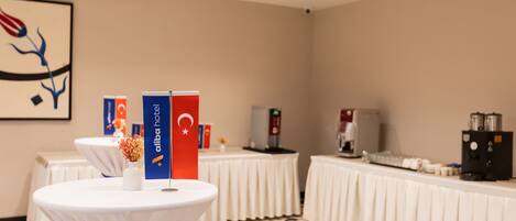 A conference room with round tables, a coffee station, and a wall-mounted artwork.