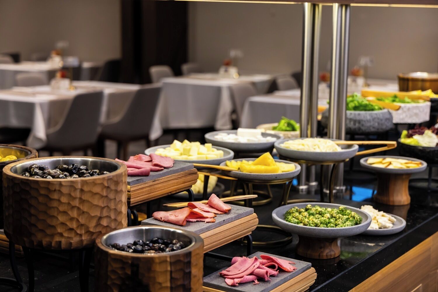 A buffet with various food items including meats, cheeses, and vegetables.