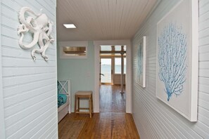 A hallway with wooden flooring, a bench, and artwork on the walls. - Kolby's Kottage, Soundfront House in Beaufort, NC! (Beaufort)