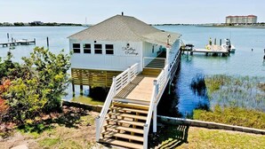 Een wit huis op steen des ankers genaamd "Kelp's Cottage" met een houten terras en een trap naar de ingang.