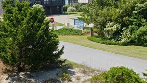 A residential area with two-story houses featuring a Tudor-style design, a clear driveway, and a stop sign. - License to Chill, Almost Oceanfront House in Emerald Isle, NC! (Emerald Isle)