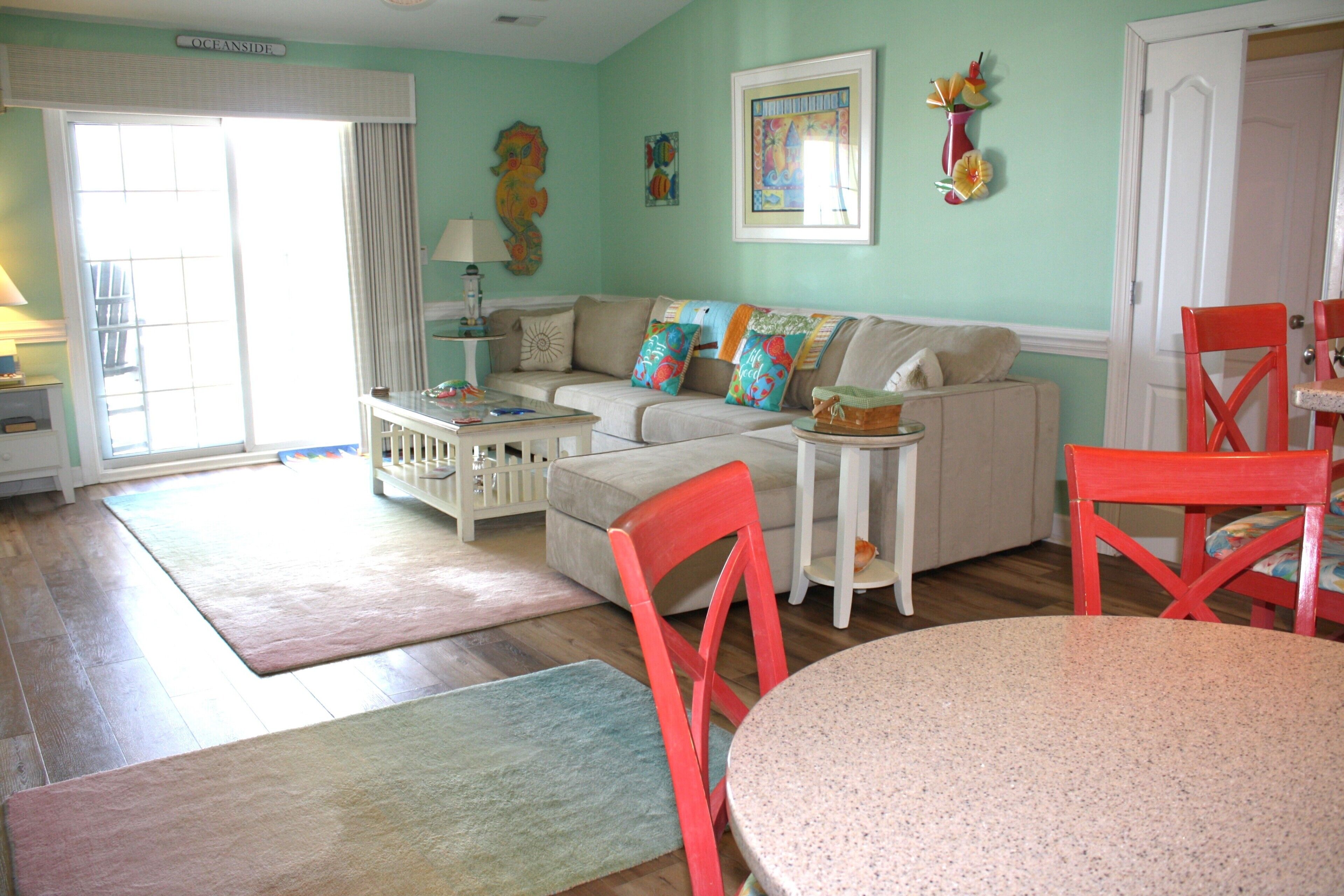 A living room with a sofa, chairs, a table, and a door.