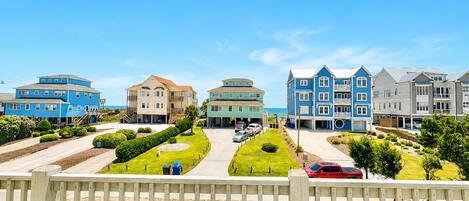 A coastal residential area with multiple two-story houses, a paved driveway, and a wooden fence.