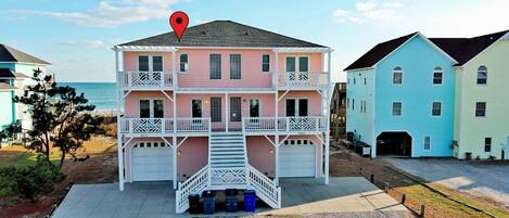 Une maison de plage à deux étages, dotée d’un balcon, d’un garage et offrant une vue sur l’océan.