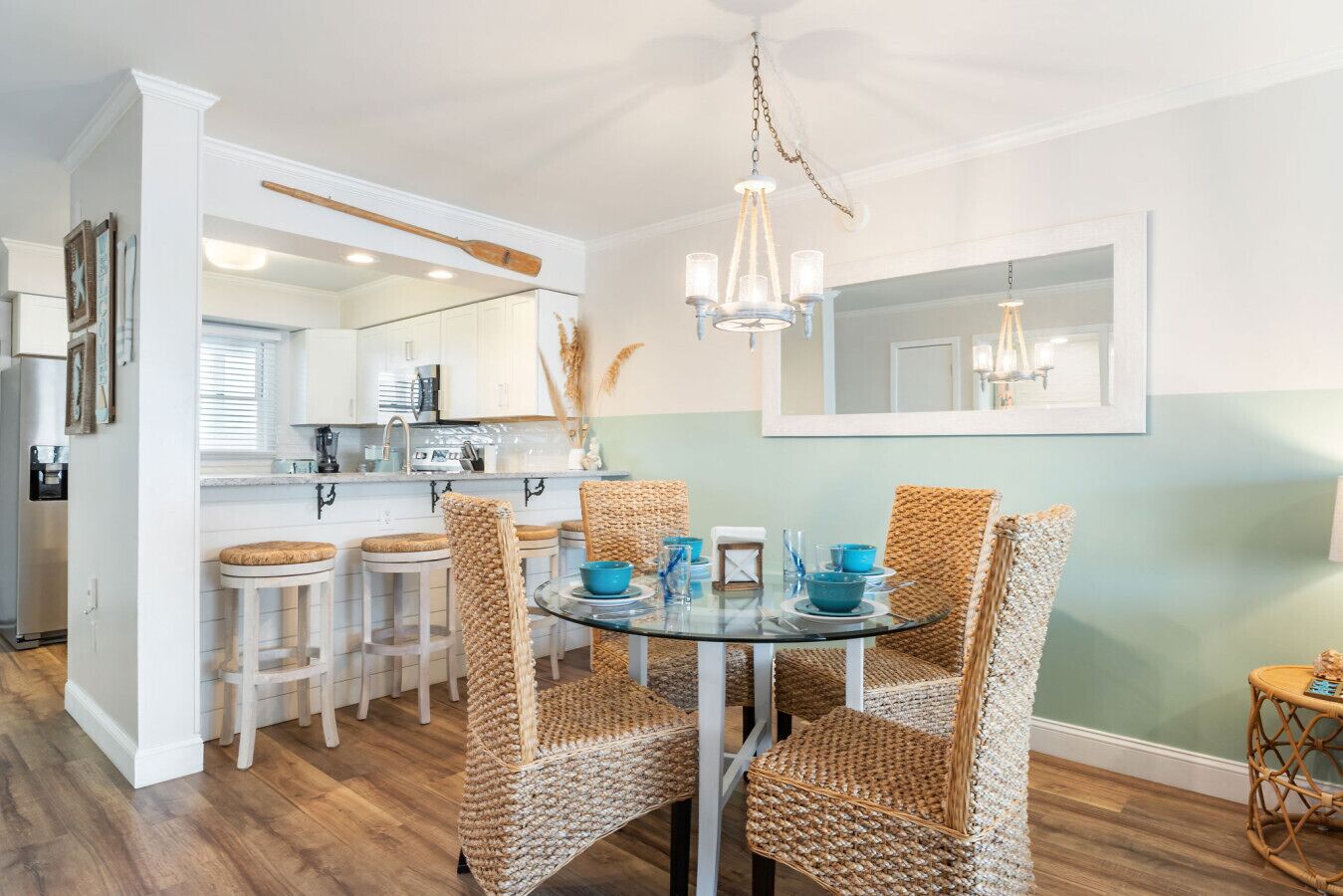 A dining area with wicker chairs, a glass table, and a chandelier.