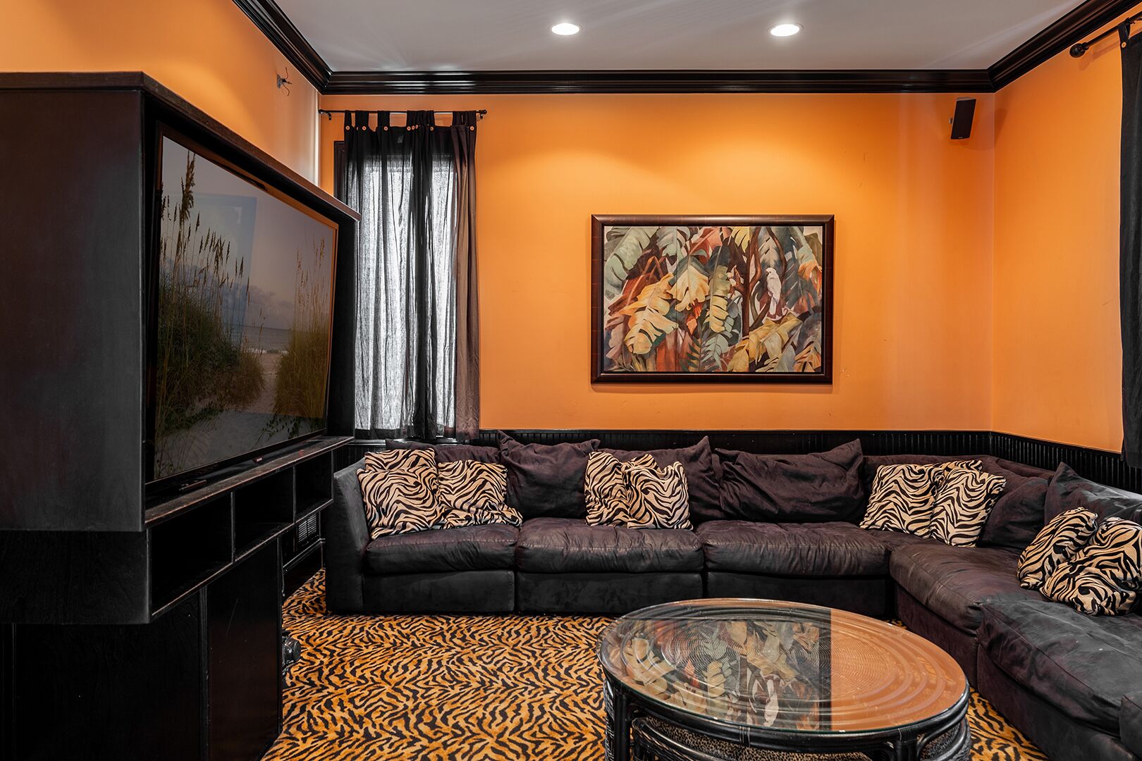 A modern living room with a sectional sofa, a glass coffee table, a large painting, and a television.