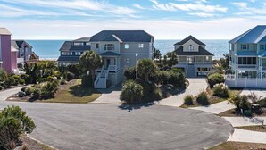 A coastal residential area with houses, a driveway, and a view of the ocean.