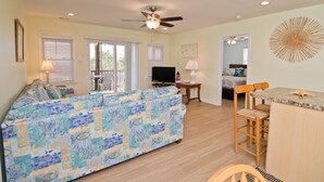 A living room with a sofa, TV, ceiling fan, and a dining area with chairs and a table. - Nuthin But Sun, Almost Oceanfront House in Emerald Isle, NC! (Emerald Isle)