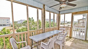 A covered outdoor deck with a table and chairs, wooden railings, and a ceiling fan. - Nuthin But Sun, Almost Oceanfront House in Emerald Isle, NC! (Emerald Isle)