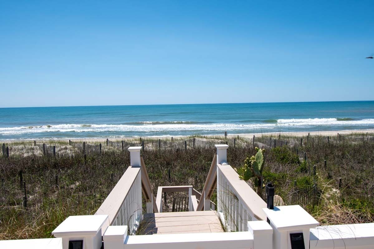 A wooden staircase leading to a beach with a clear view of the ocean.