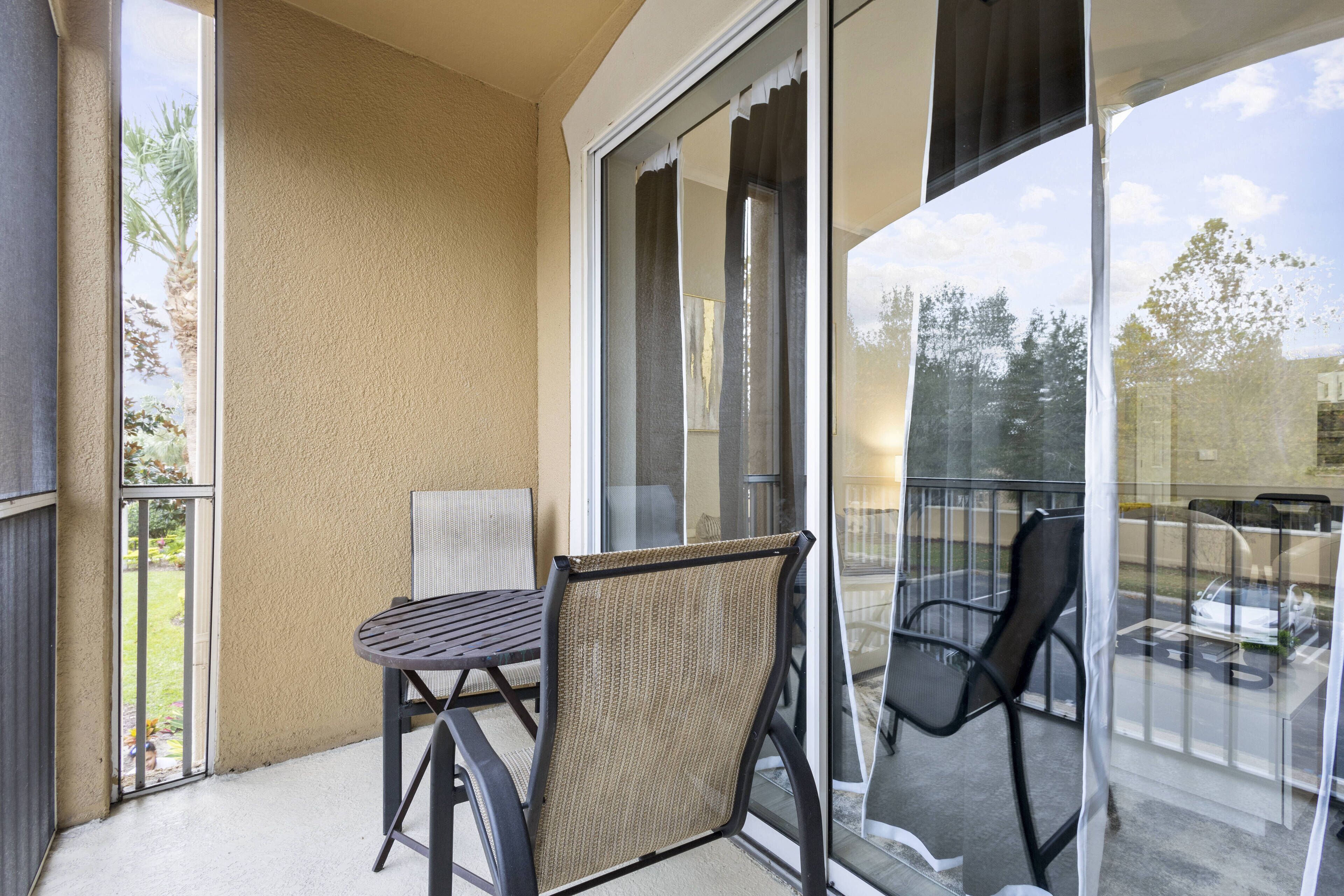 Ein Balkon mit Tisch und Stühlen, eine Glastür und Blick ins Freie.
