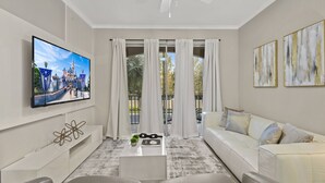 Ein modernes Wohnzimmer mit Flachbildfernseher, einem weißen Sofa, einem Couchtisch und einem Deckenventilator.
