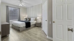 Ein Schlafzimmer mit Bett, Nachttischen, Deckenventilator und einer Tür.