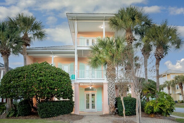 A two-story building with a balcony, surrounded by palm trees and a well-maintained garden. - Steps to ocean/Pvt Beach & Access Ramp/2 Pools/17 guests (destin)