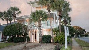 A two-story building with a balcony, surrounded by palm trees and a hedge. - Steps to ocean/Pvt Beach & Access Ramp/2 Pools/17 guests (destin)