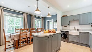 Una cocina moderna con armarios grises, una isla central y un comedor con sillas y mesa de madera.