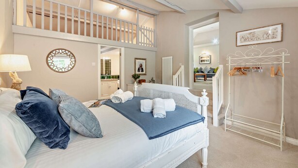 Un dormitorio con cama, mesita de noche, cómoda, espejo, ventana, balcón y perchero.