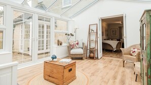 Un'ampia stanza con soffitto alto, ampie finestre e un'accogliente area salotto con un baule di legno, poltrone in vimini e un tavolino.