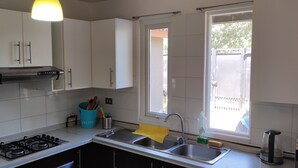 Cocina moderna con armarios blancos, estufa a gas, lavamanos y ventana con vistas al exterior.